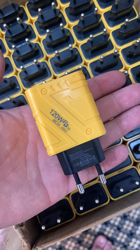 Yellow and black power adapter held in a hand with a patterned background